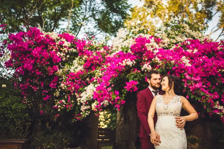 Bride and groom standing beneath a wall of bright pink bougainvillea