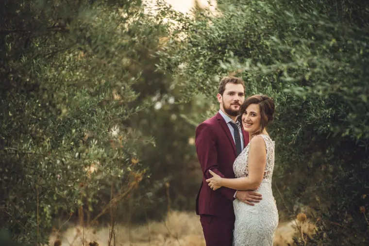 Bride and groom embracing among the olive trees near Vasilias Nikoklis Inn