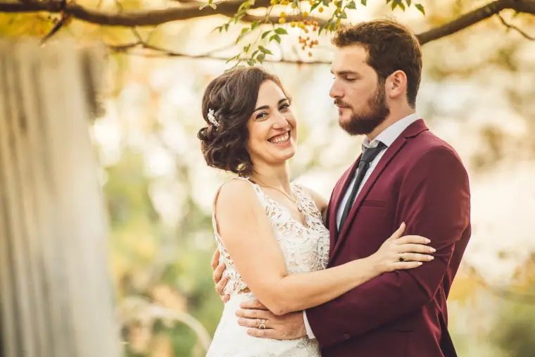 Couple laughing together in soft golden light beside a tree trunk