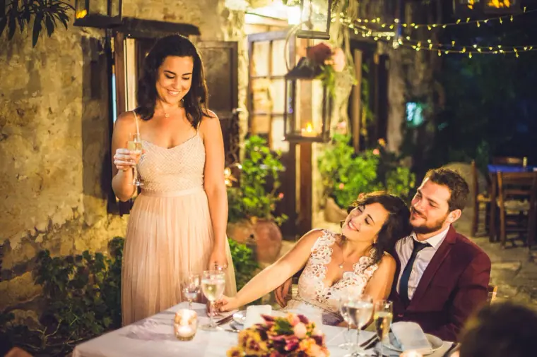 Bridesmaid in blush pink giving a speech as the couple listen at dinner