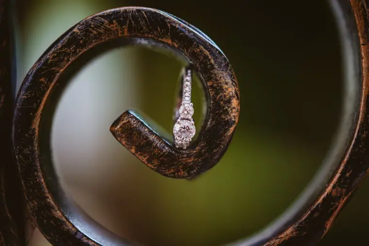 Diamond engagement ring balanced in a curled wrought-iron scroll
