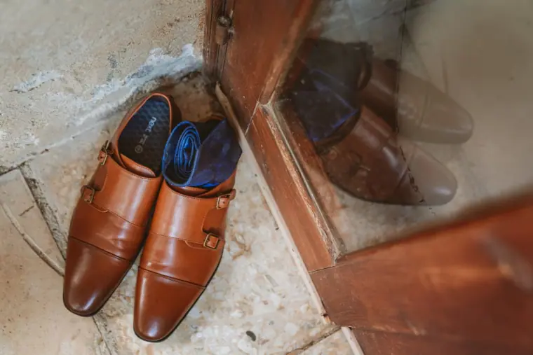 Groom's tan leather monk-strap shoes on a stone floor