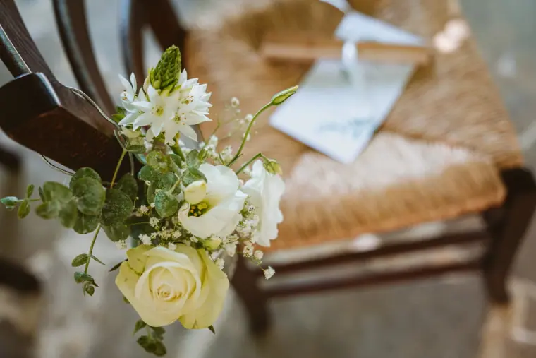 Bouquet of white and yellow roses resting on a rush-seated chair