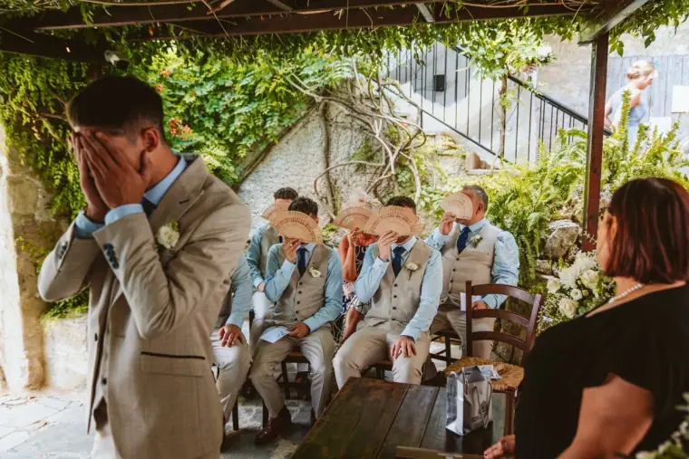 Groom covering his eyes for the reveal as groomsmen and guests watch