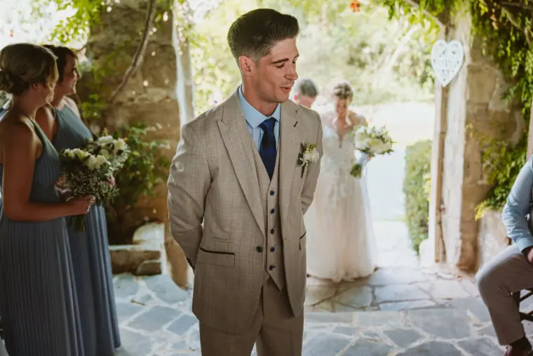 Groom waiting in the courtyard as the bride approaches through the archway