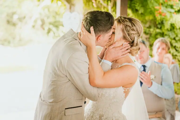 First kiss as husband and wife, groomsmen smiling in the background