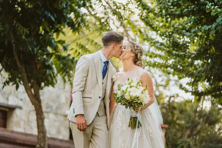 Chloe and Liam kissing under the trees after the ceremony at Vasilias Nikoklis Inn