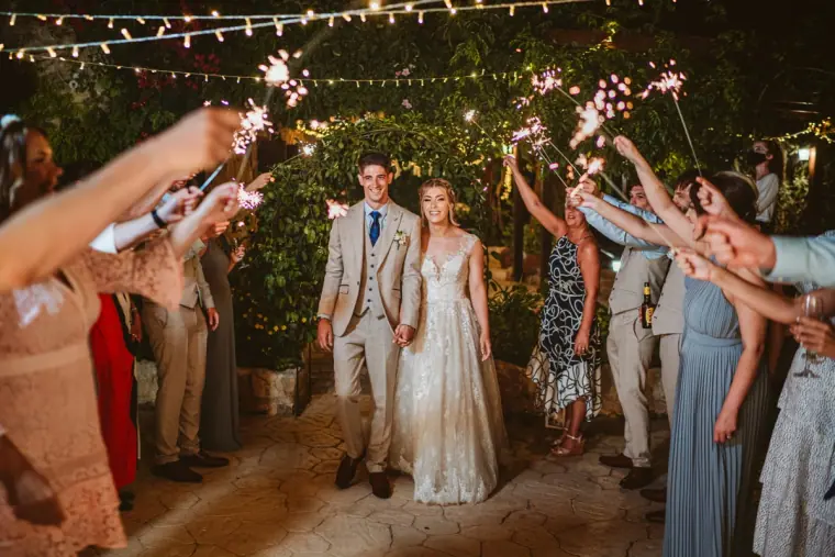 Bride and groom walking through a tunnel of guests holding sparklers