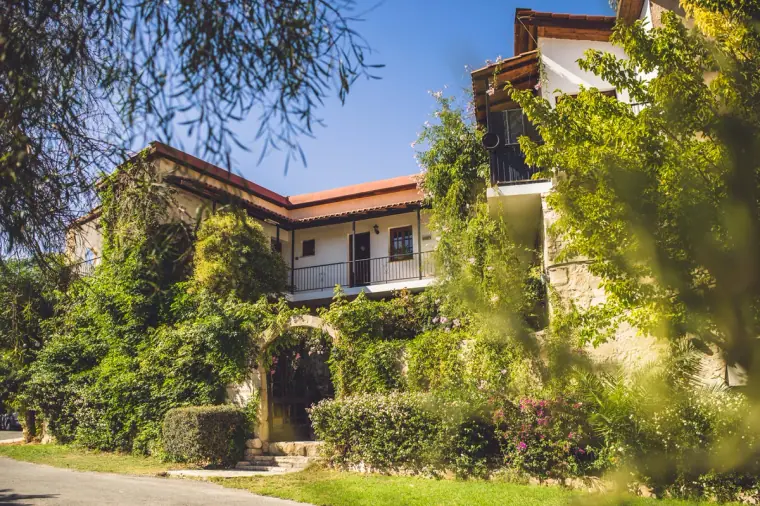 Stone guesthouse with wooden balconies at Vasilias Nikoklis Inn under blue sky