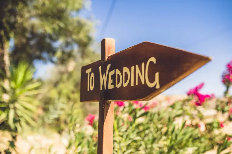 Wooden "To Wedding" arrow sign among pink oleanders