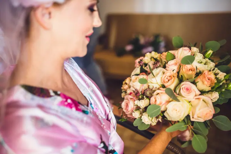 Bride admiring her bouquet of blush and peach roses