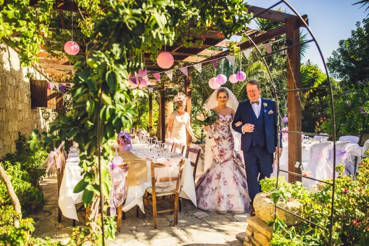 Bride in a floral gown walked through the lantern-hung pergola towards the ceremony