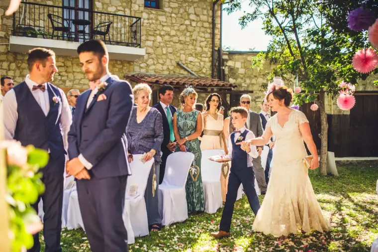 Flower girl and page boy walking down the aisle as the groom watches