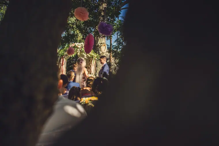 Garden ceremony glimpsed through a dark foreground silhouette