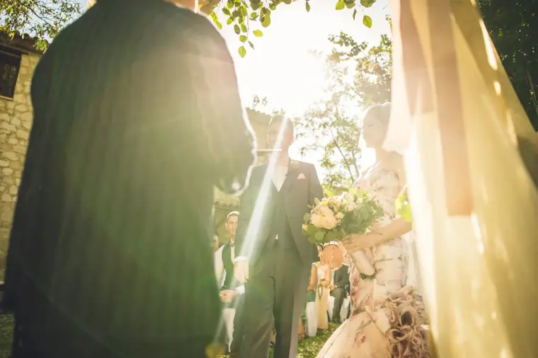 Bride and groom facing each other in a burst of sunlight during the vows