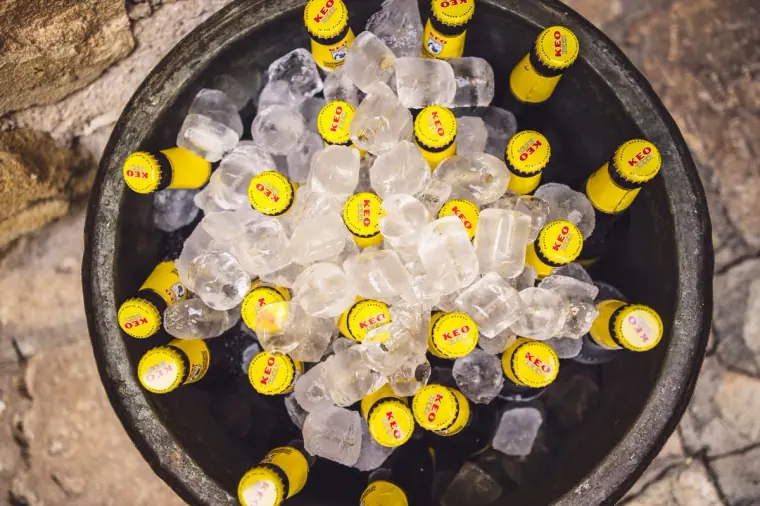 Bottles of KEO beer chilling on ice in a round tub, seen from above