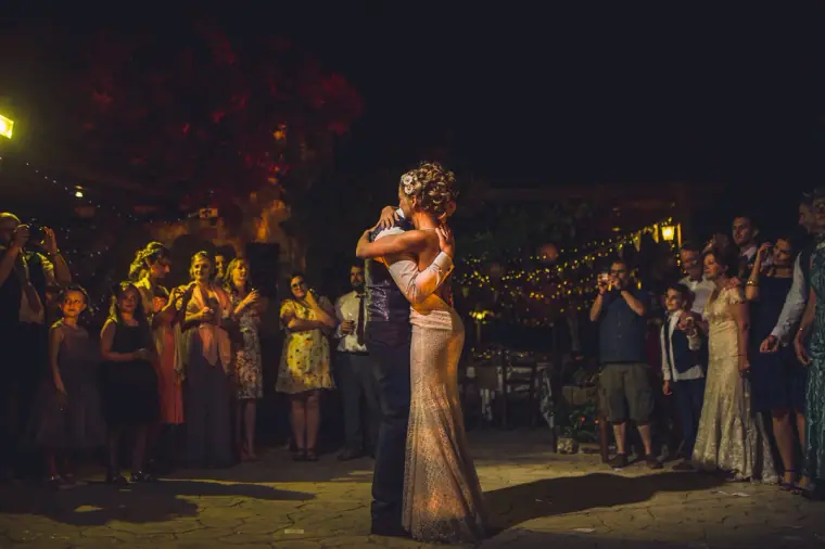 Bride and groom's first dance in the courtyard, surrounded by guests at night
