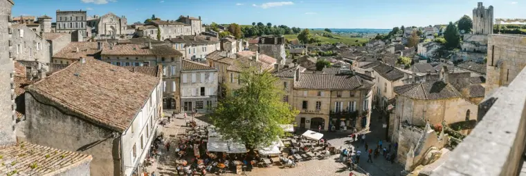 Wide rooftop panorama of an old stone town in the Bordeaux wine region under blue sky