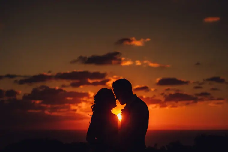 Silhouette of a couple about to kiss as the sun sets behind them over the Ibiza sea