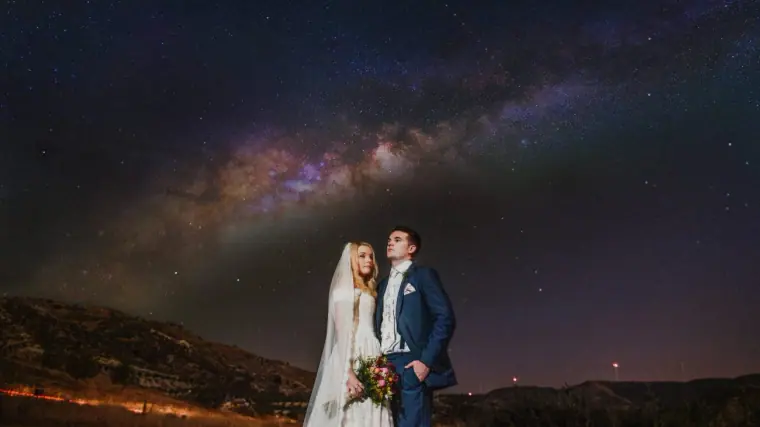Bride with her bouquet and groom in navy beneath a starry Milky Way sky near Kouklia, Cyprus