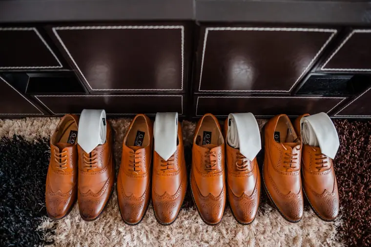 Row of tan brogues with white ties tucked inside, lined up for the groomsmen