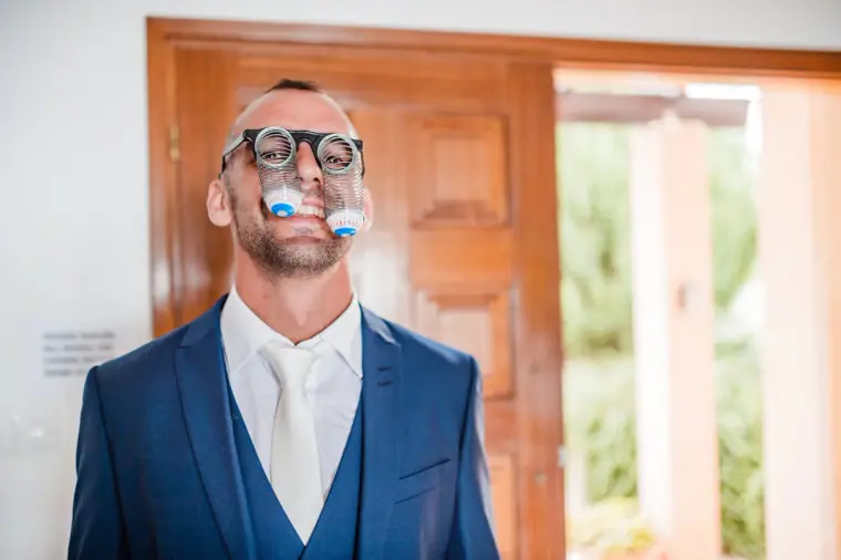 Groom clowning around in novelty glasses while getting ready