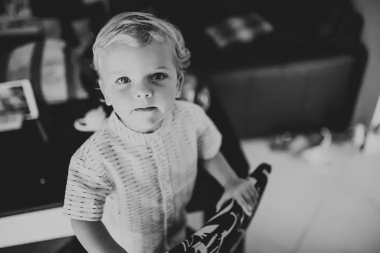 Black-and-white photo of a toddler in a knitted top looking at the camera