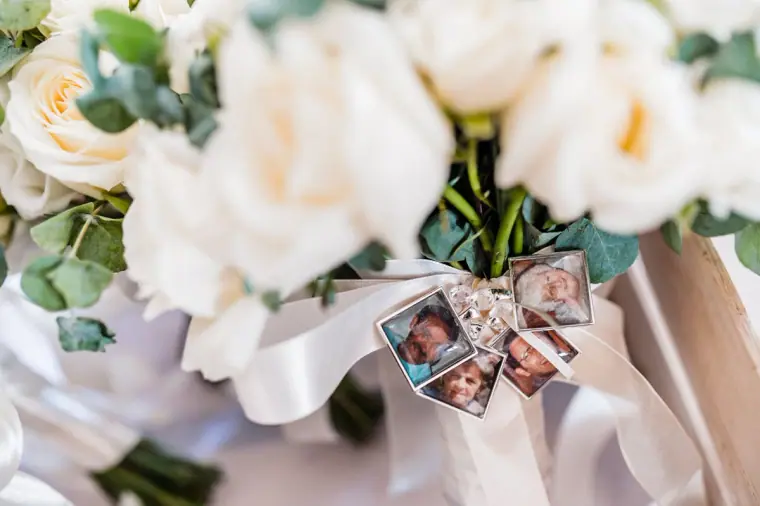 Photo memory charms tied to the stem of a white rose bouquet