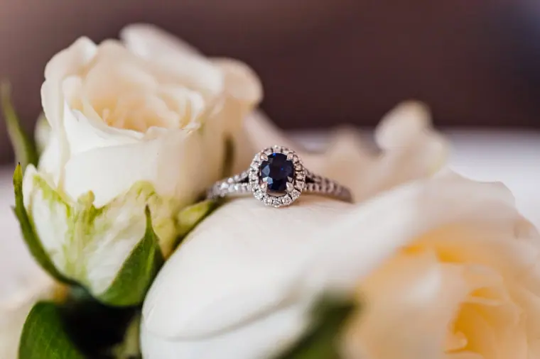 Sapphire and diamond engagement ring resting on white roses