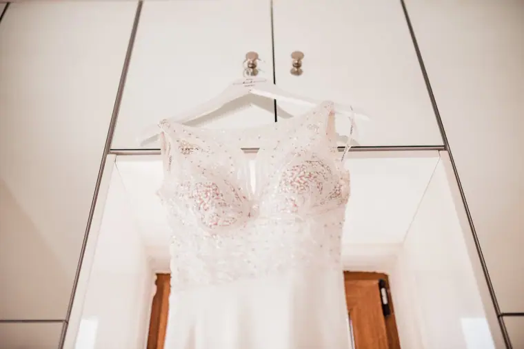 Lace bodice of the wedding gown on a hanger against white wardrobes