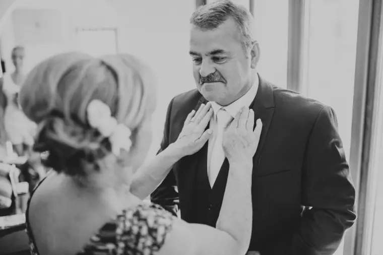 Black-and-white photo of a guest adjusting an older man's tie