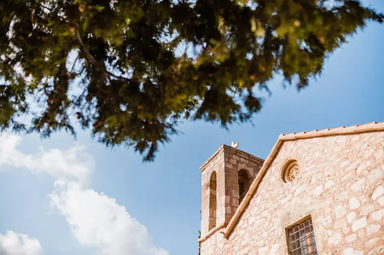 Stone bell tower of the old monastery at Minthis Hills against blue sky