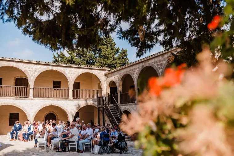 Guests gathered beneath the arched cloisters of the monastery courtyard