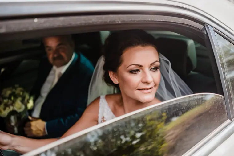 Bride in her veil looking out of the wedding car window as she arrives