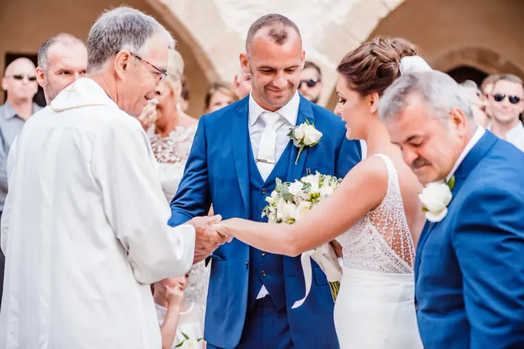 Bride being handed to the groom at the front of the courtyard ceremony