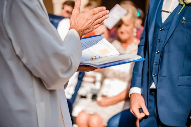 Priest gesturing as he reads from the order of service during the ceremony