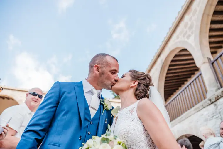 Groom kissing the bride beneath the arches after the ceremony at Minthis Hills