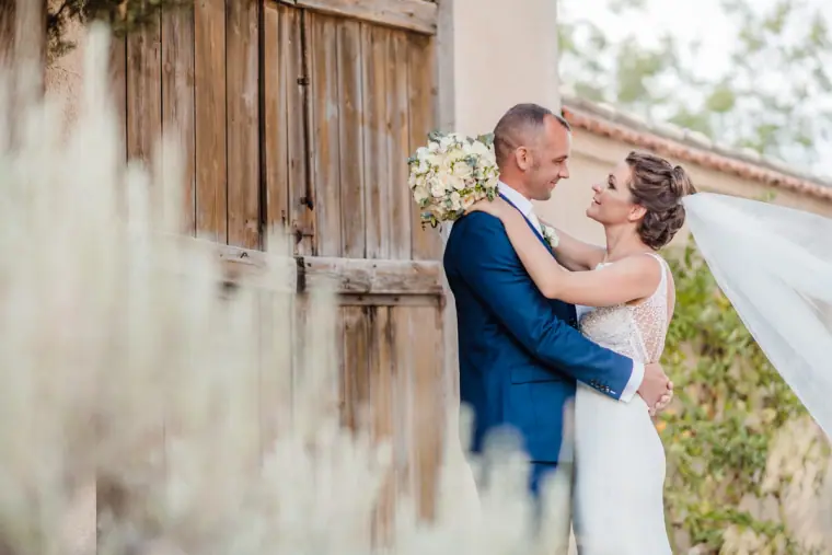 Couple embracing beside weathered wooden shutters, soft lavender in the foreground