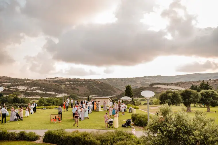 Guests on the lawn at Minthis Hills beneath a dramatic cloudy sky, hills beyond