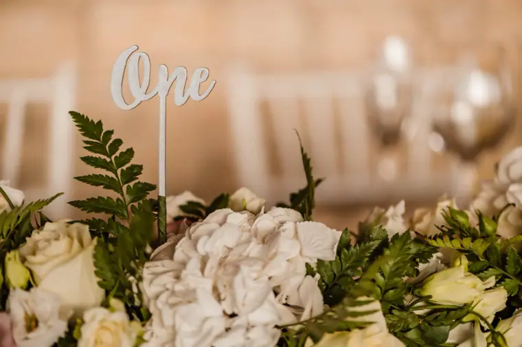 Acrylic "One" table number above white hydrangeas, roses and ferns