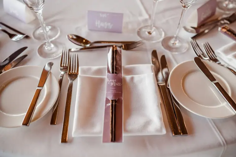 Place setting with silver cutlery, a lilac name card and a folded napkin
