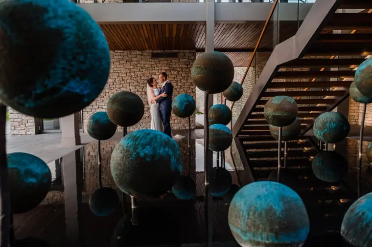Bride and groom in the Minthis Hills lobby among teal sphere sculptures and a stone staircase