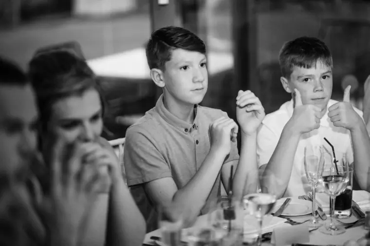 Black-and-white photo of guests laughing and giving a thumbs-up during the speeches