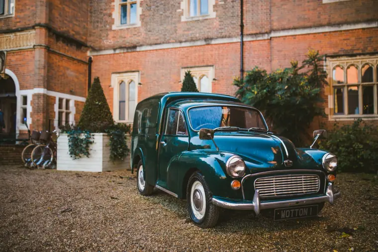 Vintage green Morris Minor van parked outside the red-brick facade of Wotton House