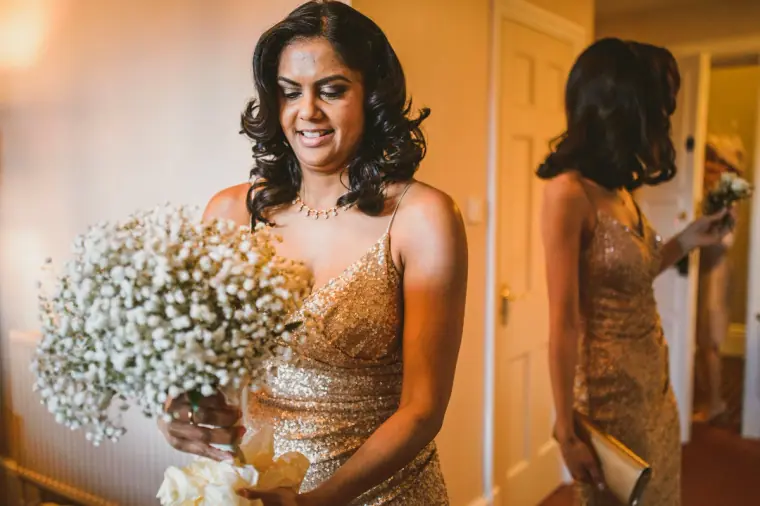 Bridesmaid in a gold sequin dress holding a gypsophila bouquet