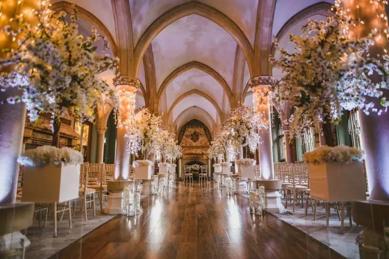 Ceremony room at Wotton House with white blossom trees, chandeliers and Chiavari chairs