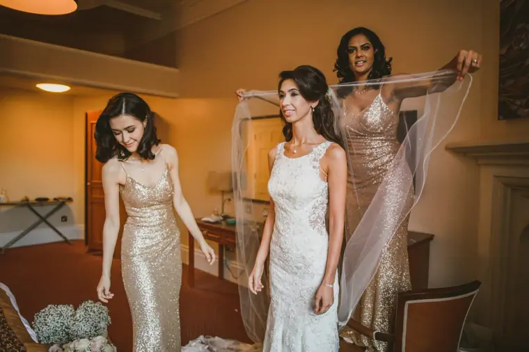 Bridesmaids in gold sequins arranging the bride's veil