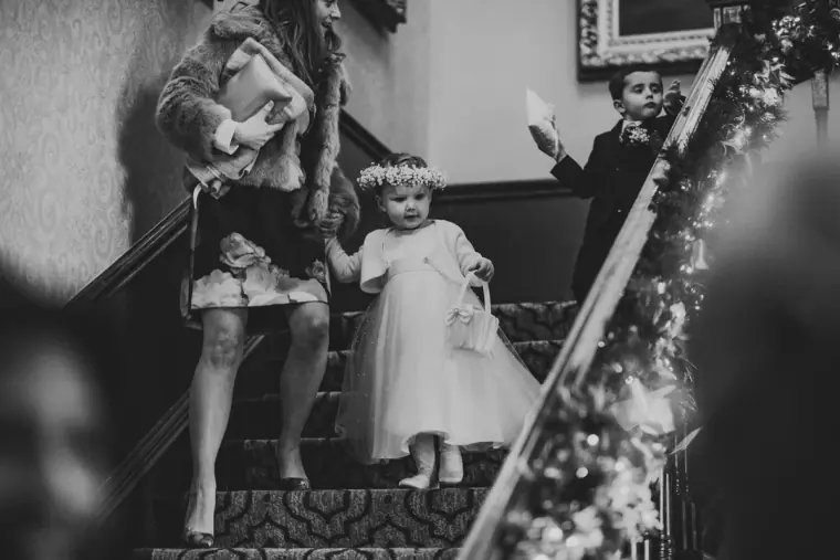 Black-and-white photo of a flower girl and page boy coming down the stairs