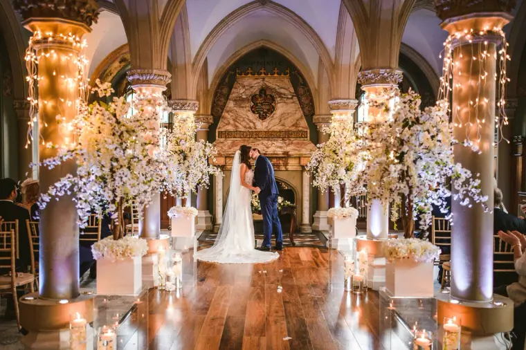 Elina and Iain's first kiss beneath the gothic arches and fairy-lit columns at Wotton House, Dorking