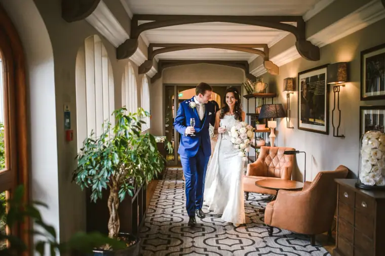 Bride and groom walking hand in hand along a panelled corridor at Wotton House